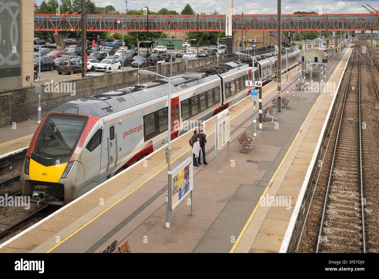 Deux voyageurs attendent près d'un train Greater Anglia à la gare de Cambridge dans l'est de l'Angleterre pour commencer leur voyage. Banque D'Images