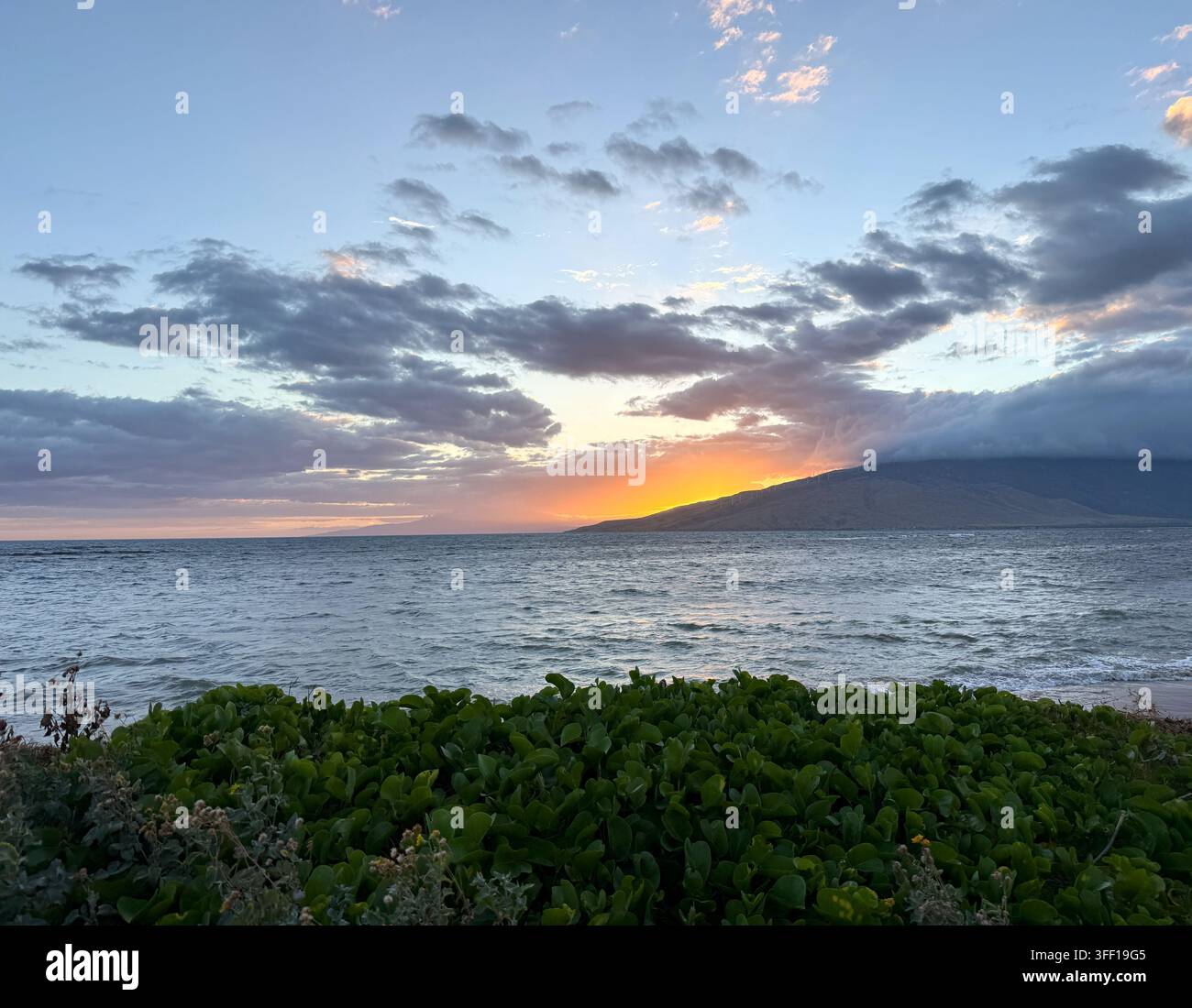 Couchant sur l'océan Pacifique avec des montagnes couvertes de nuages au Waipuilani Park, Maui, Hawaï - Image de stock capturée avec un smartphone