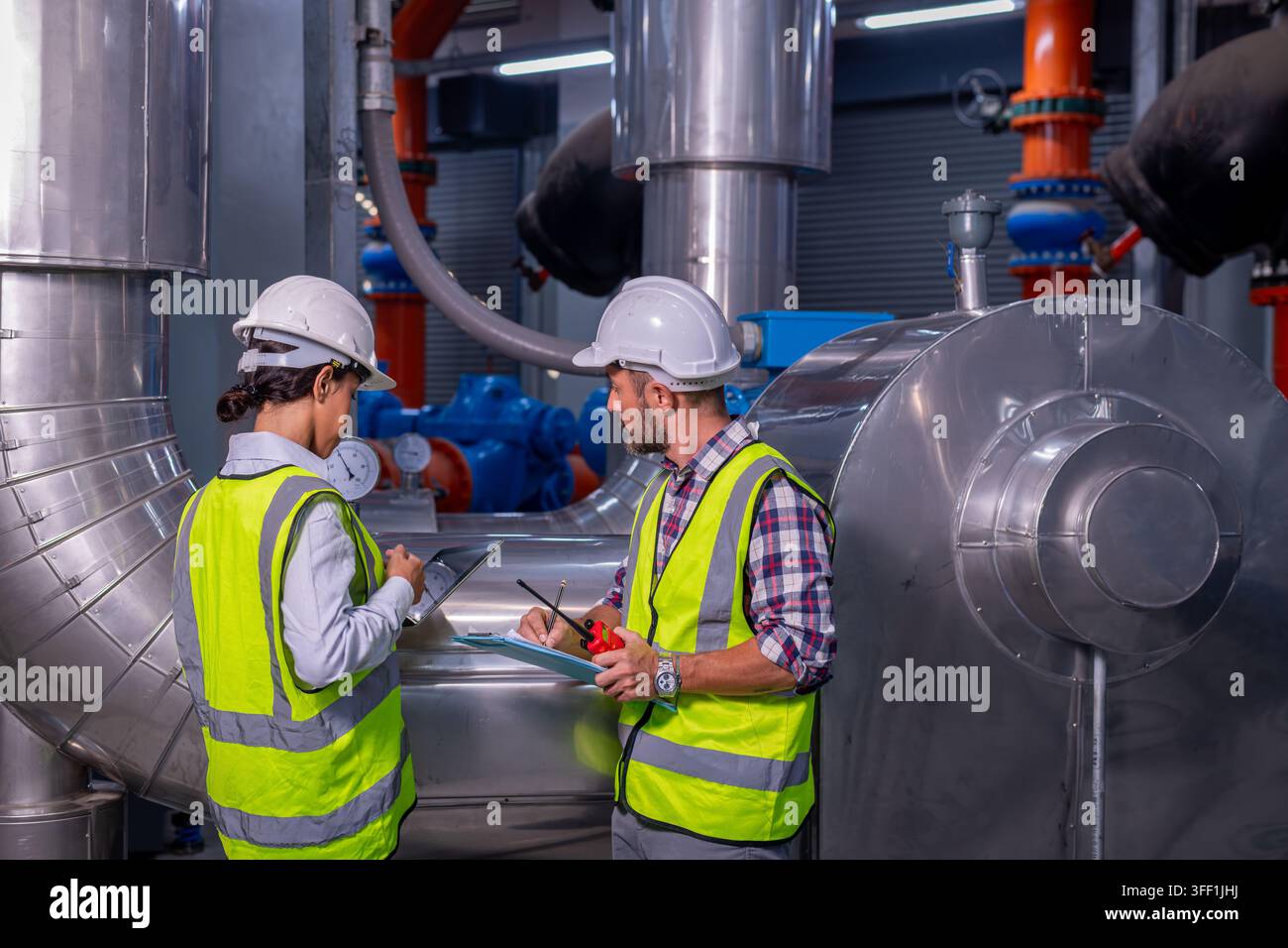 Ingénieur vérifiant le climatiseur de tour de refroidissement industriel, qui est un refroidisseur d'air de tour de refroidissement d'eau HVAC d'un grand bâtiment industriel. Banque D'Images