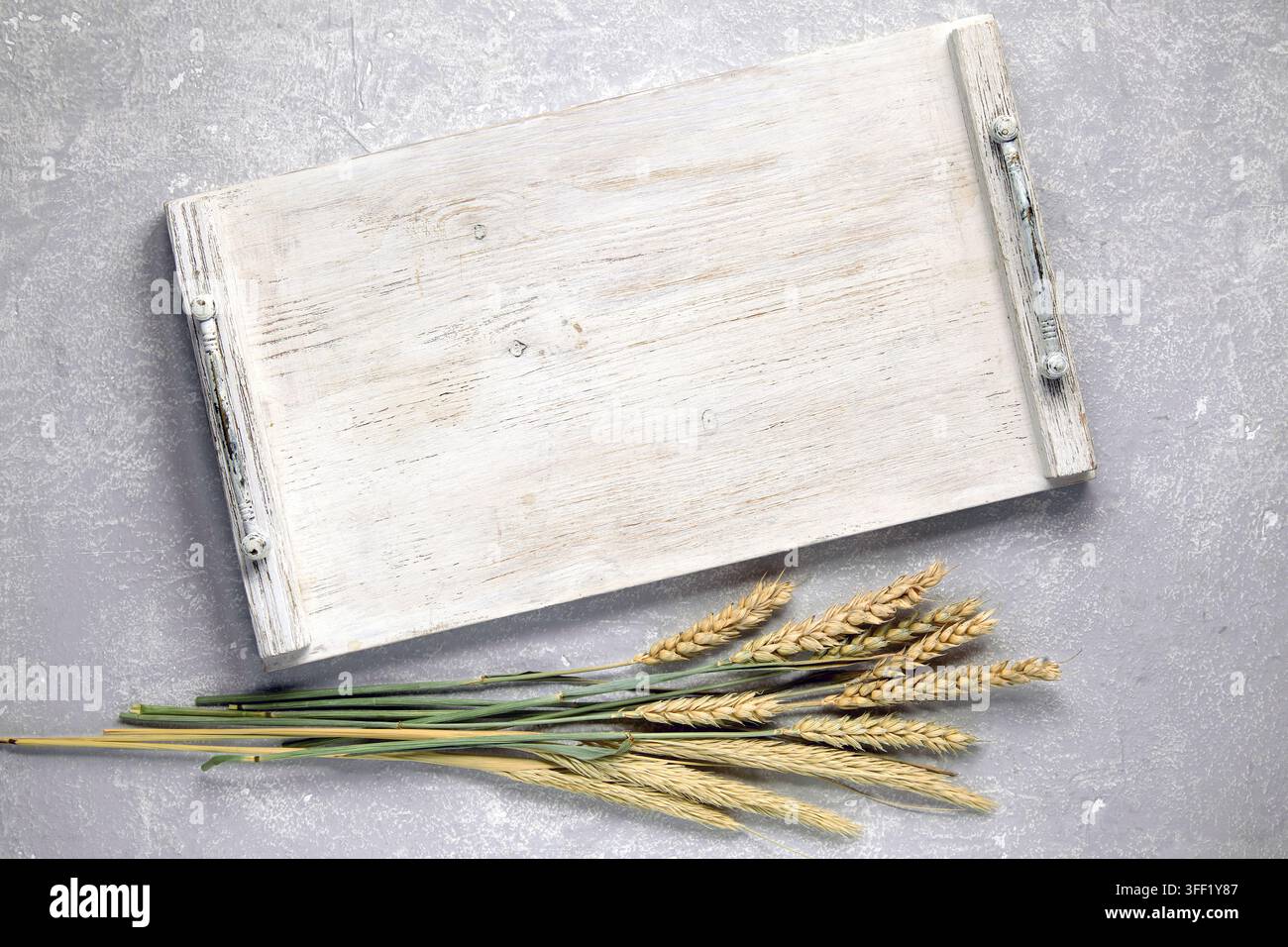 Plateau en bois blanc vide, planche avec poignées et épis de maïs secs sur un dessus de table en pierre grise vu du dessus Banque D'Images