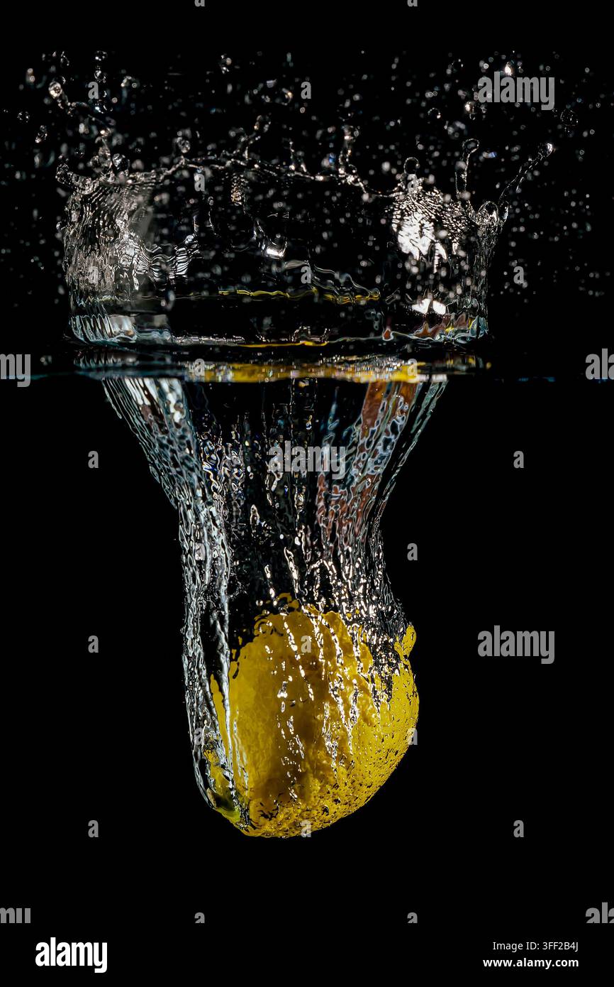 Un citron tombe dans l'eau avec un grand éclaboussement Banque D'Images