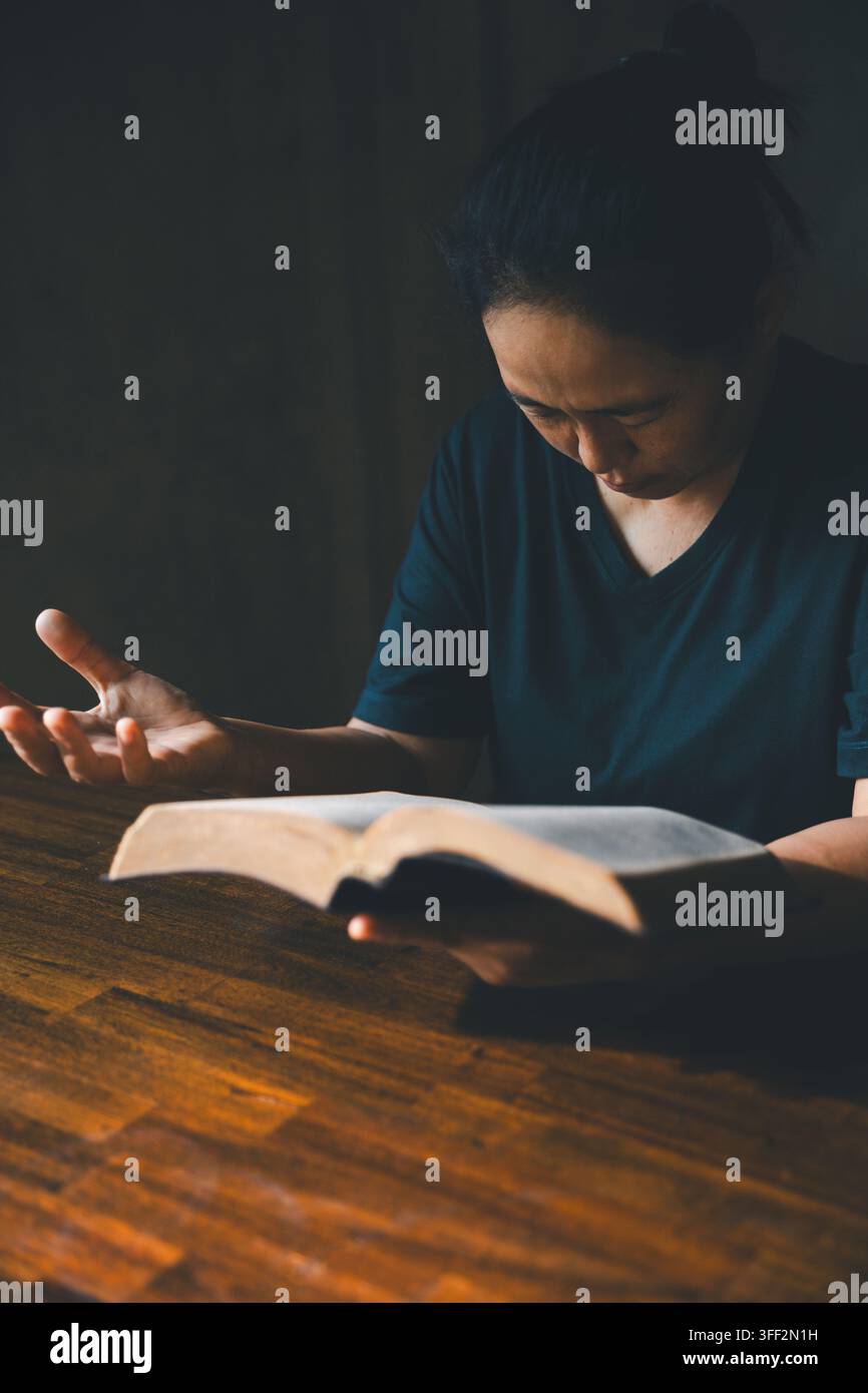 Person tenant une Bible ouverte d'une main tendue dans un geste d'enseignement, représentant l'étude des Écritures, la foi chrétienne, la prédication, la dévotion, l'adoration Banque D'Images
