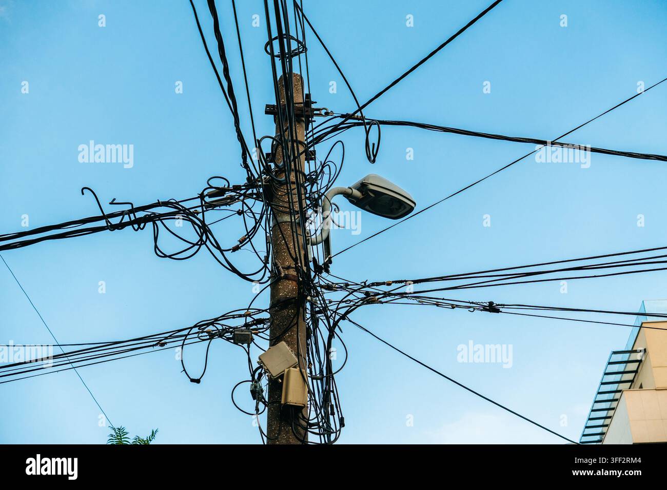 Un poteau électrique recouvert de câbles aériens emmêlés et un lampadaire se dressent à Belgrade. L'image convient à la téléphonie, à l'électricité, aux infrastructures et Banque D'Images