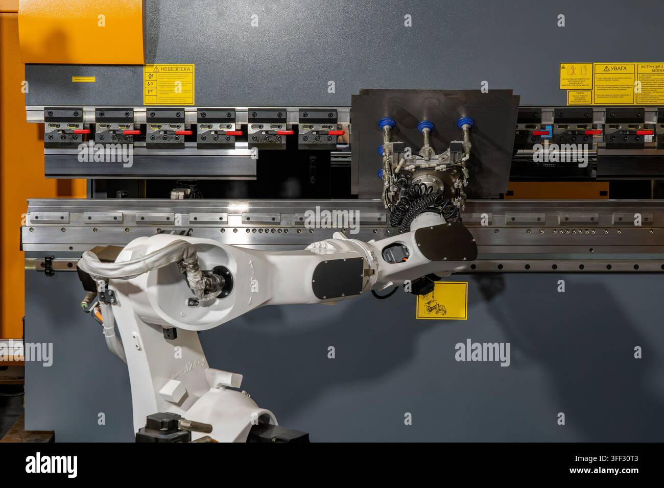 Bras robotique industriel opérant une cintreuse de tôle automatisée pour le formage et la fabrication de métaux de précision Banque D'Images