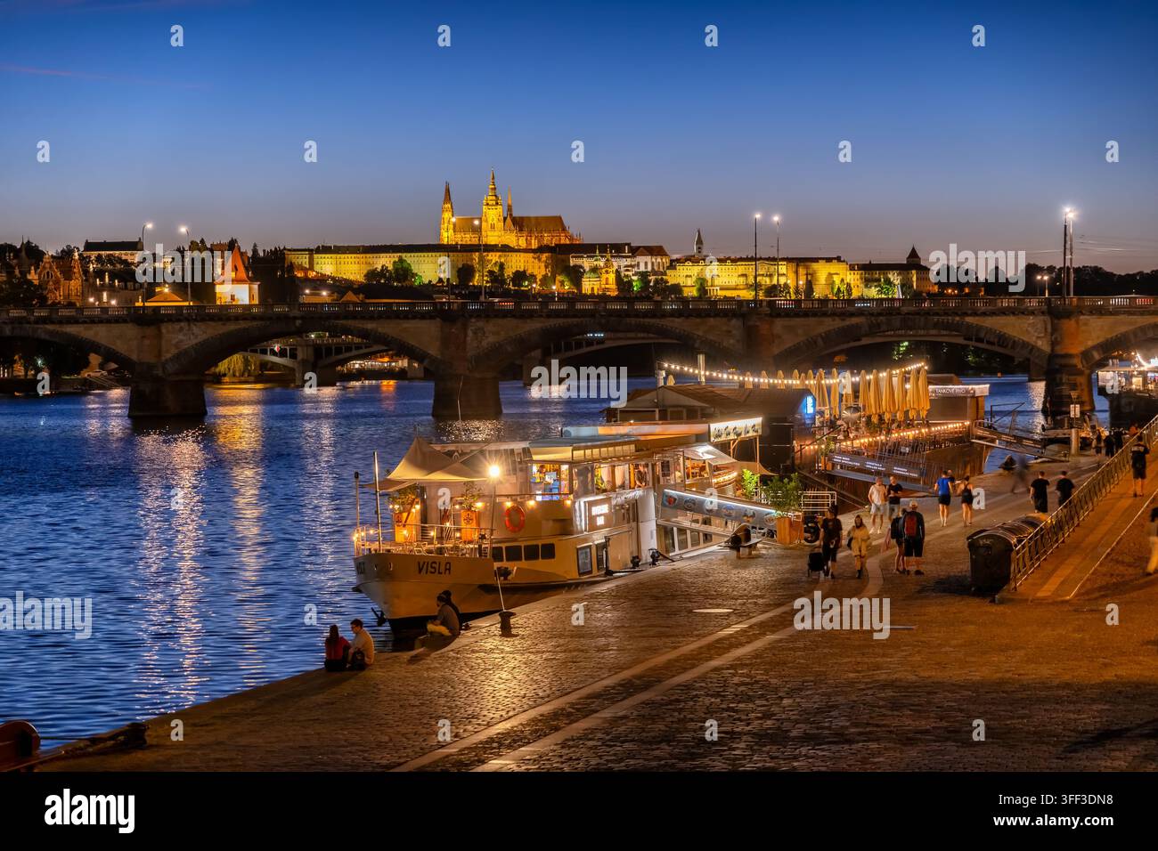 Prague, République tchèque - 27 mai 2026 : Ville de nuit à la promenade de la Vltava avec un bar sur bateau et vue sur le château de Prague. Banque D'Images