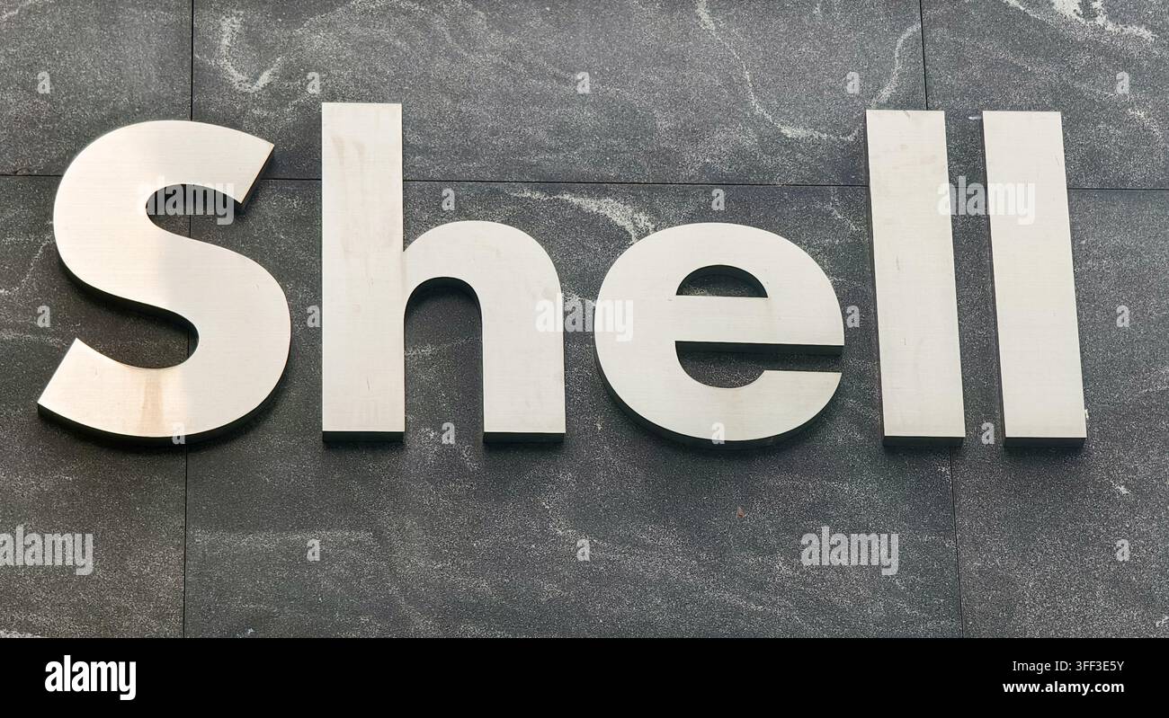marque verbale métallique de Shell plc, l'entreprise multinationale mondiale d'énergie et de pétrole, montée sur un mur de pierre sombre texturé Banque D'Images