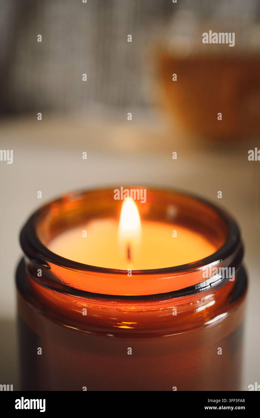 Flamme de bougie éclairant un bocal en verre ambré, créant une atmosphère chaleureuse et confortable Banque D'Images