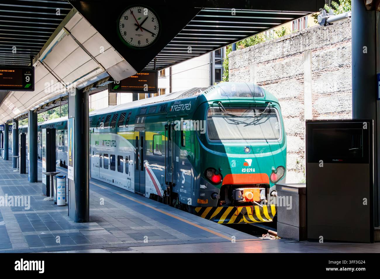 Train régional Trenord au quai 9 de la gare de Lombardie en Italie avec horloge de gare et panneaux de quai Banque D'Images