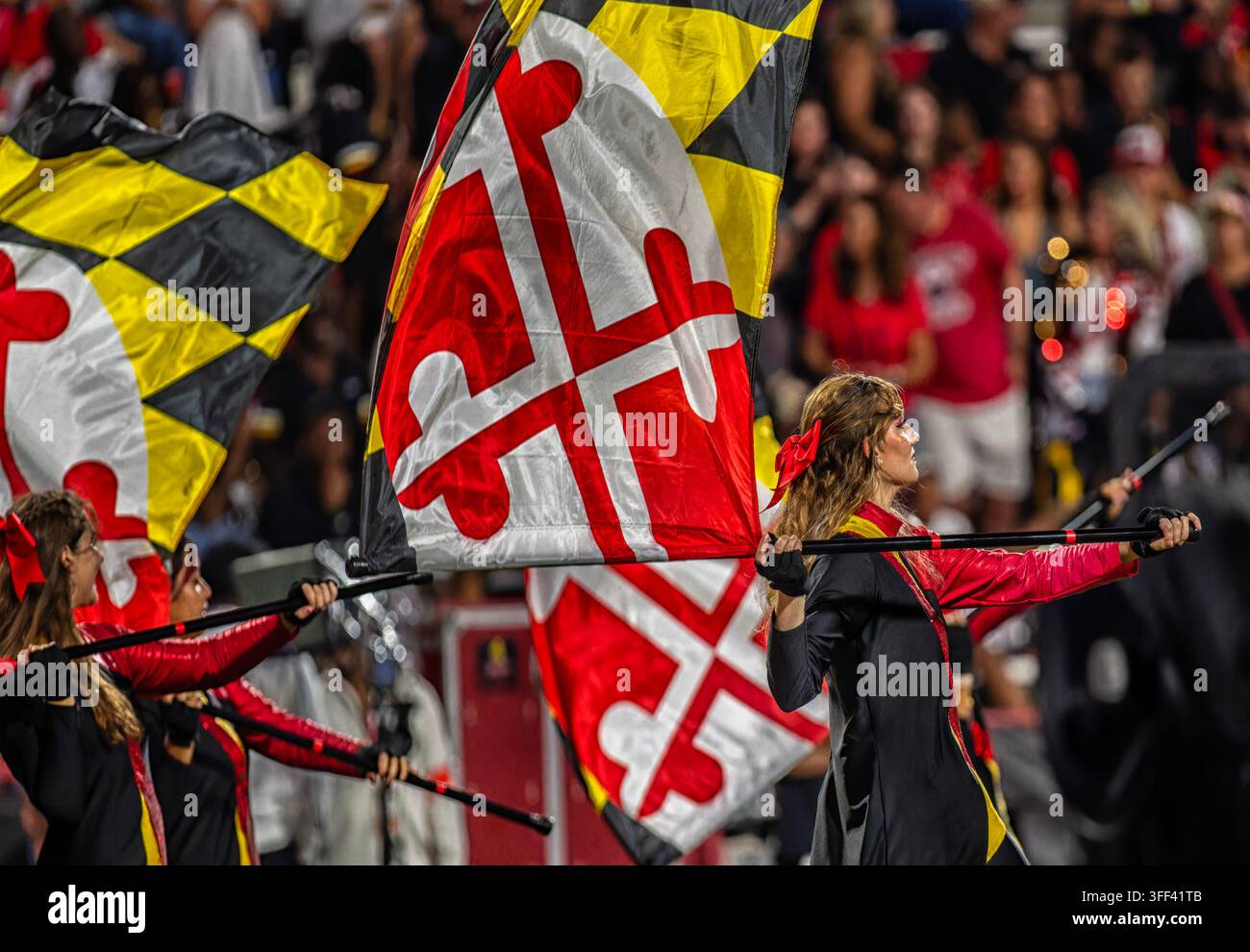 Membres de la garde colorée de l'Université du Maryland exécutant avec de grands drapeaux de l'État du Maryland lors d'un événement sportif sur le campus. Banque D'Images