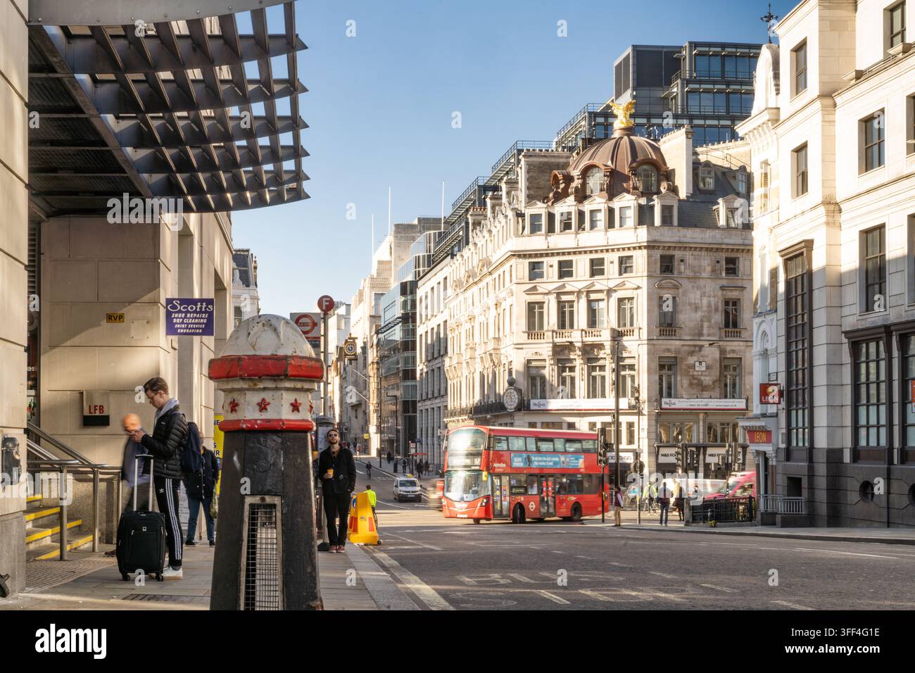 Les navetteurs attendent à l'extérieur de la gare City Thameslink sur Ludgate Hill, à Londres, alors qu'un bus rouge passe devant les bâtiments historiques. Banque D'Images