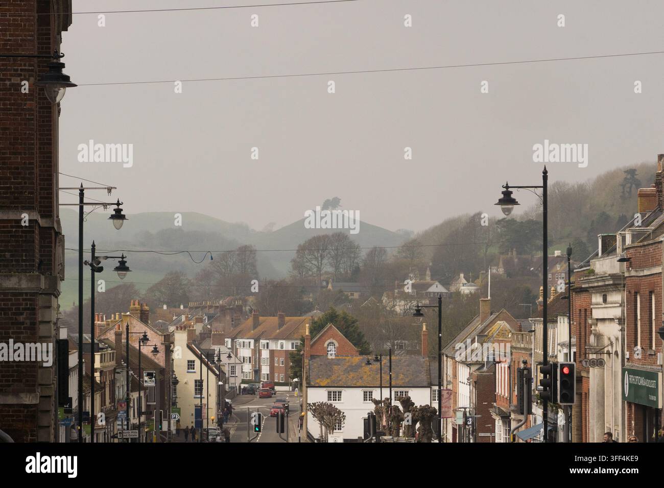 Une vue élevée descendant la Bridport High Street dans le Dorset, en Angleterre, en direction de l'emblématique Colmer’s Hill coiffé d'arbres par une journée brumeuse. Banque D'Images