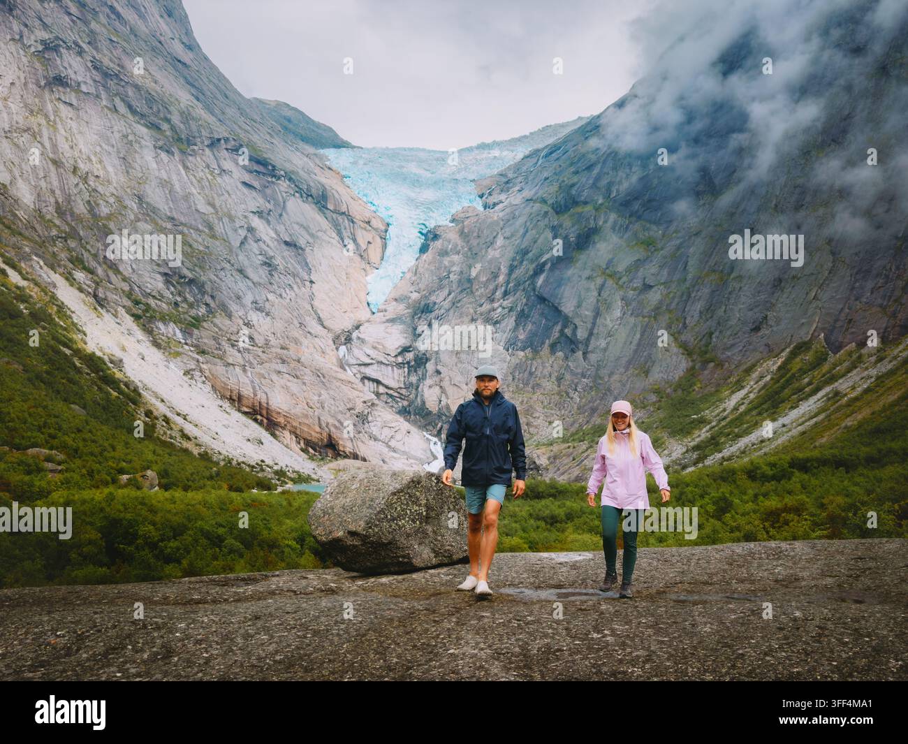 Couple randonnant avec une vue sur le glacier de Briksdalsbreen en Norvège, homme et femme, groupe de touristes voyageant ensemble et profitant de vacances romantiques dans les montagnes entre amis Banque D'Images