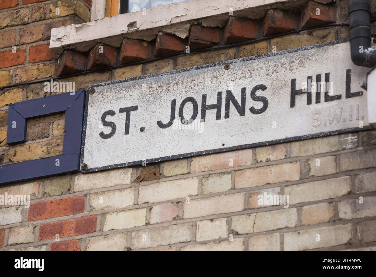 Un panneau de rue vintage pour St. Johns Hill, Battersea, Londres (SW11), monté sur un bâtiment en briques pour guider les piétons à travers la zone historique. Banque D'Images