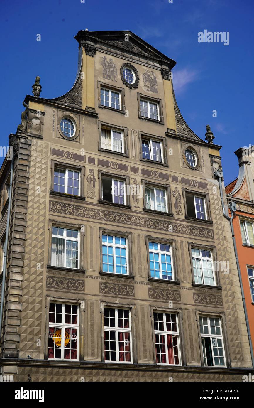 Vue détaillée d'une façade de maison historique ornée d'une décoration en sgraffito et d'un toit en croupe traditionnel, contre un ciel bleu clair. Banque D'Images