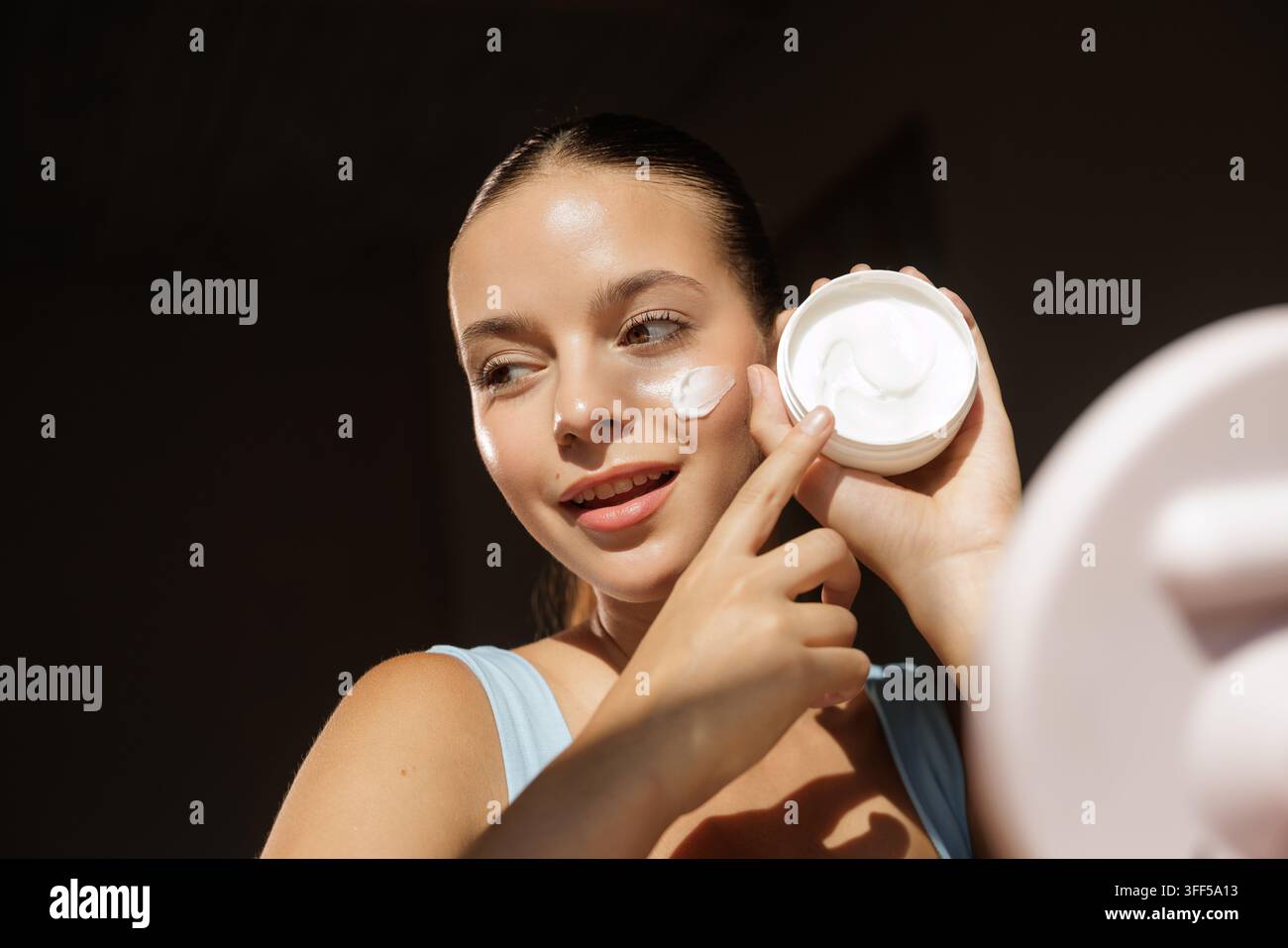 Une femme applique une crème pour le visage coréenne faite maison sur son visage, mettant l'accent sur le tonique et les soins parfaits pour une peau problématique. Banque D'Images