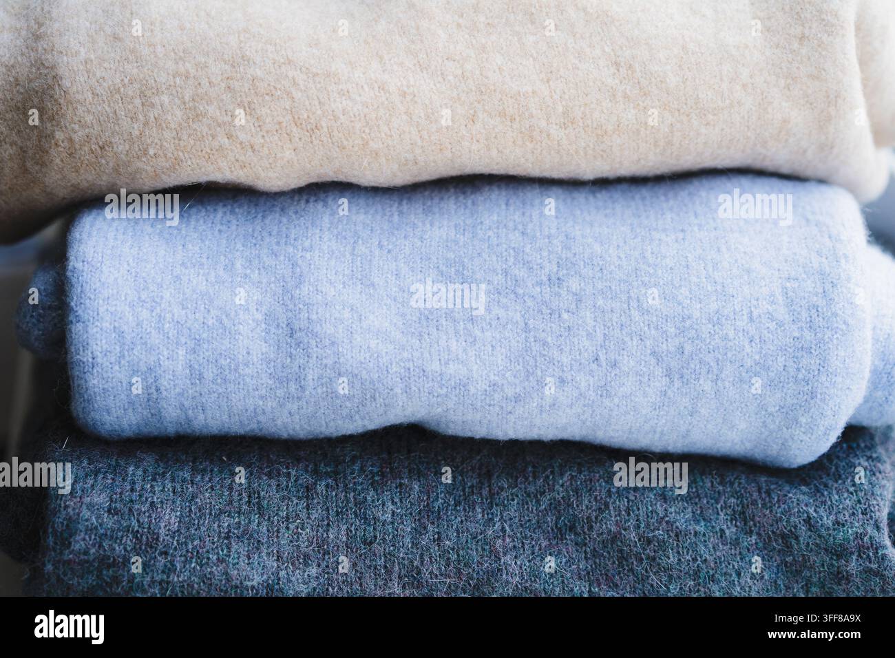 Pulls en tricot pliés empilés avec des vêtements d'hiver douillets beige et bleu Banque D'Images