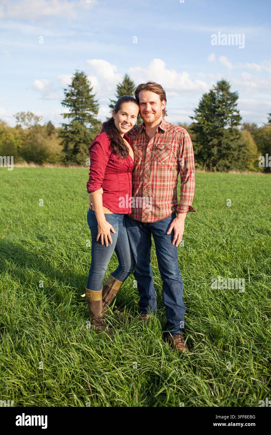 Couple heureux debout ensemble dans un champ herbeux Banque D'Images