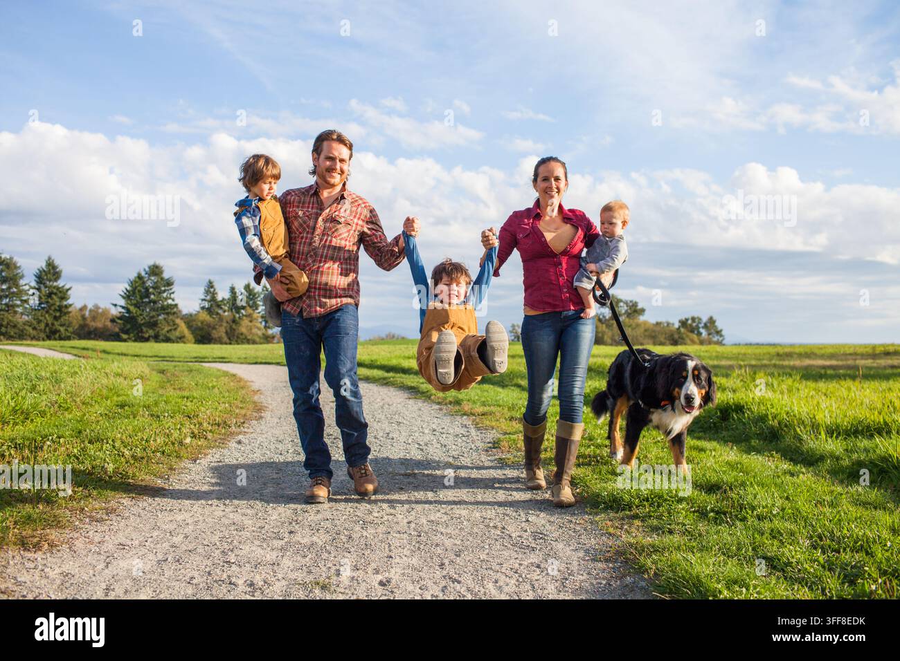Famille heureuse de cinq personnes avec trois fils promenant leur chien Banque D'Images