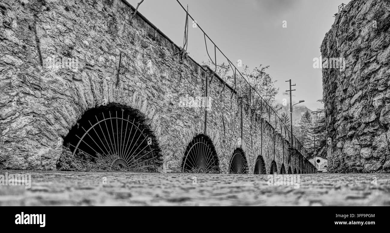 Arches en pierre historiques le long d'une étroite ruelle pavée à Chiavenna, Lombardie, Italie, mettant en valeur l'architecture alpine traditionnelle. Banque D'Images