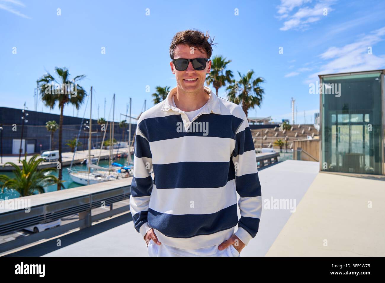 Jeune homme portant des lunettes de soleil dans une marina Banque D'Images