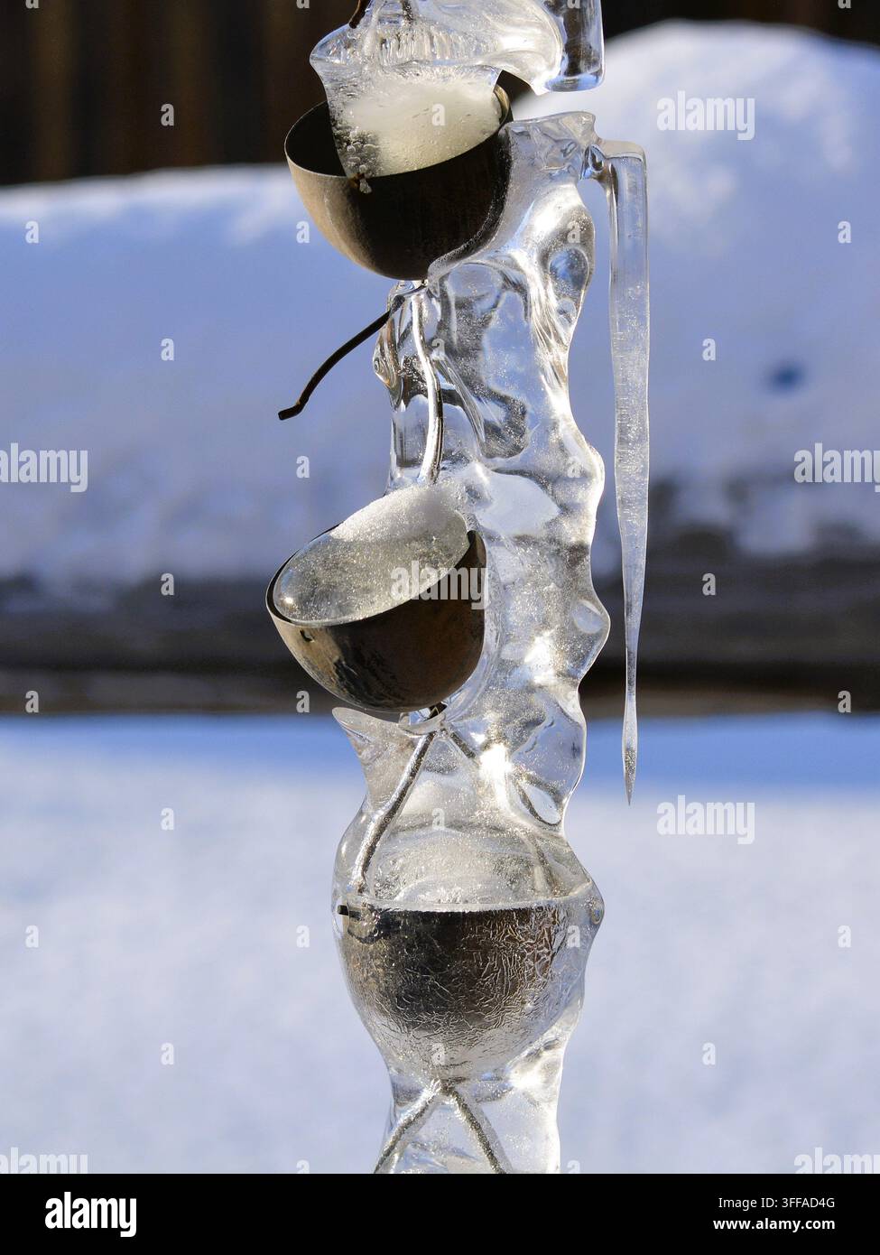 Gros plan d'une chaîne de pluie rustique avec des glaçons qui dégoulinent et de la neige en arrière-plan Banque D'Images