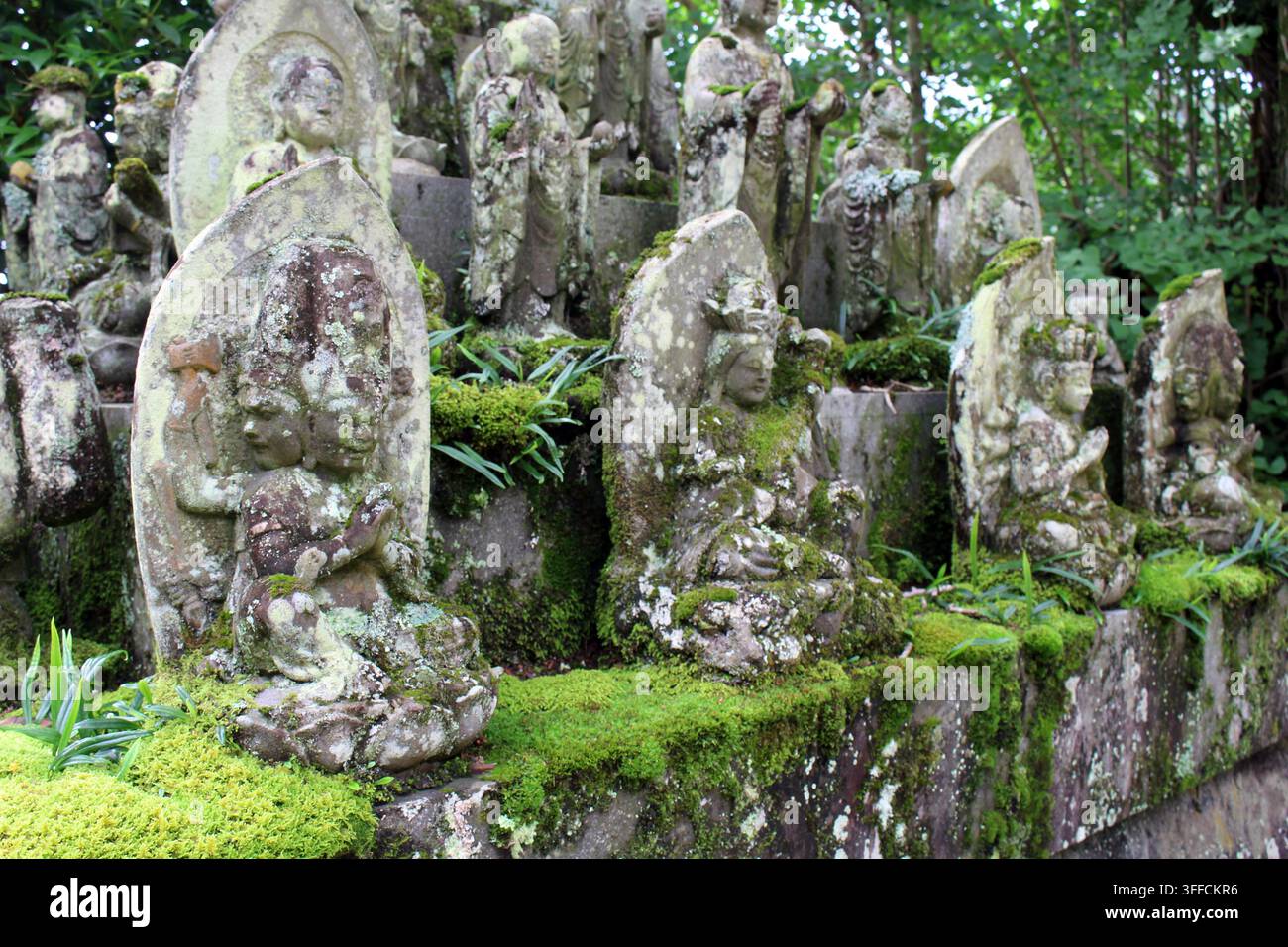 Statues bouddhistes décorées de fleurs fraîches se dressent le long d'un chemin dans la cour montagneuse du temple d'Okuboji, la quatre-vingt-huitième et dernière étape du Banque D'Images