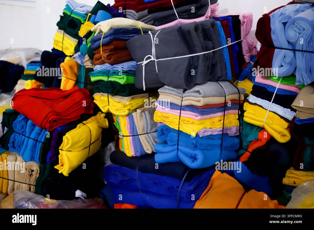 Roules de tissu colorées et matériaux textiles empilés dans un atelier de production de vêtements Banque D'Images