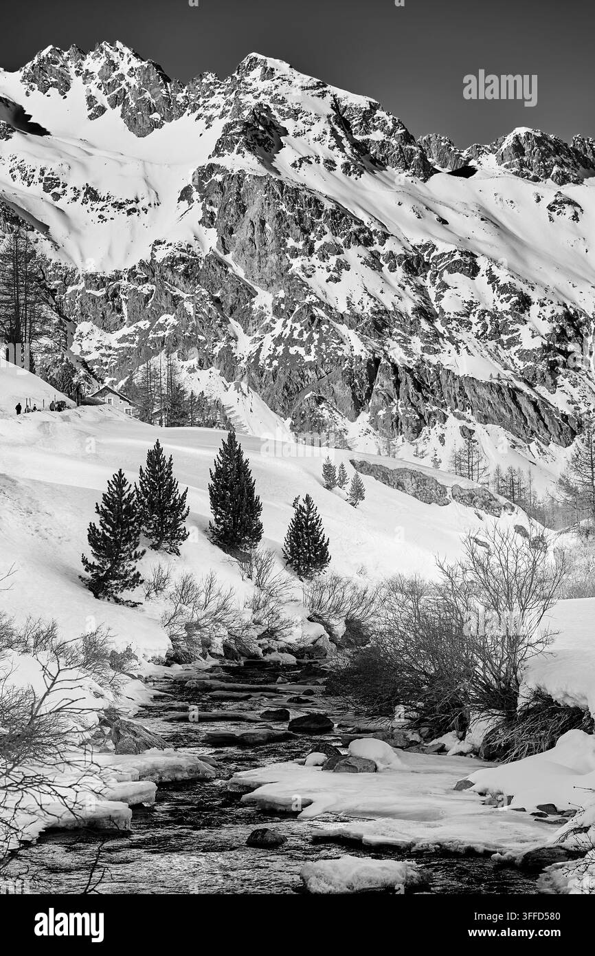 Sommetes alpins enneigés et ruisseau de montagne à Engadin, Suisse, créant un paysage hivernal dramatique dans les Alpes suisses. Banque D'Images