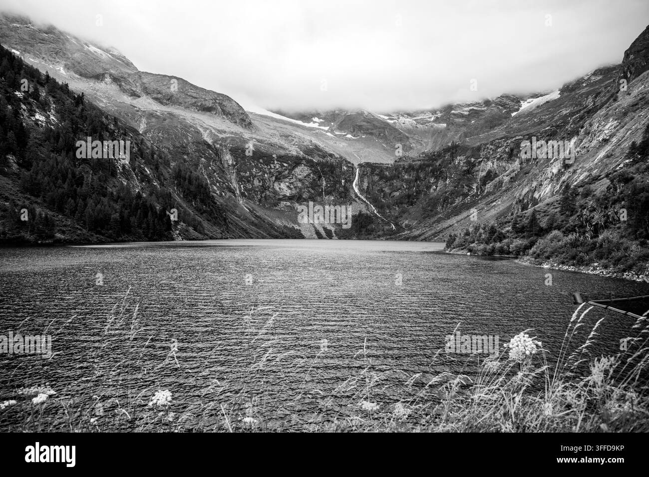 L'image montre le Lower Rotgudensee, un réservoir à Muhr, Salzbourg. Le niveau de l'eau est à 1733 m au-dessus du niveau de la mer. Des montagnes entourent le lac de tous côtés. Le ciel est couvert. Banque D'Images