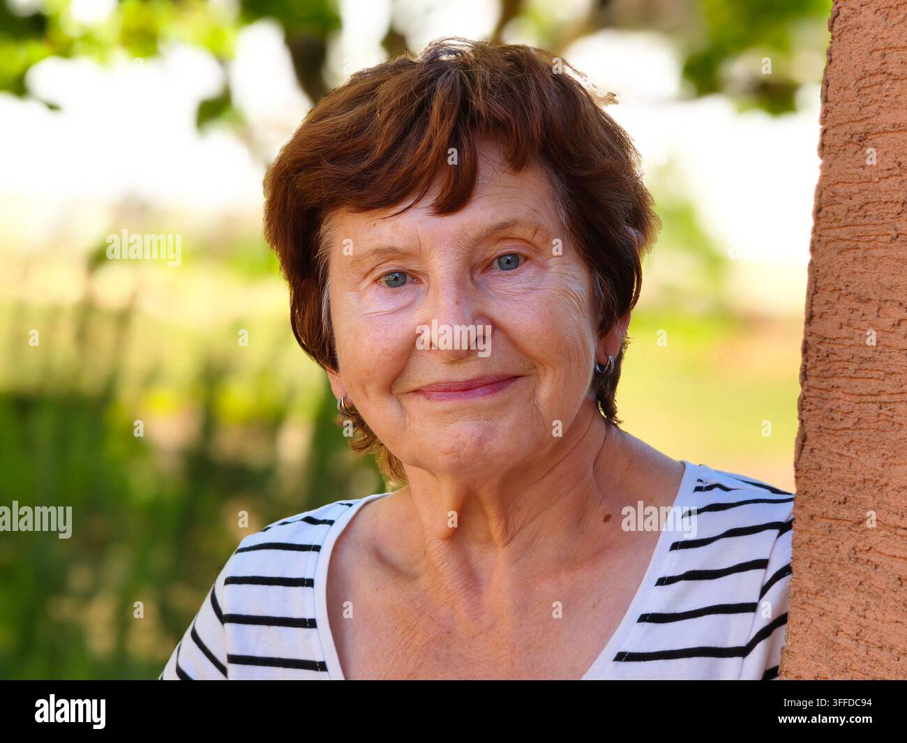 Portrait serein d'une femme âgée souriante s'appuyant contre un mur en plein air - Image de stock capturée avec un smartphone