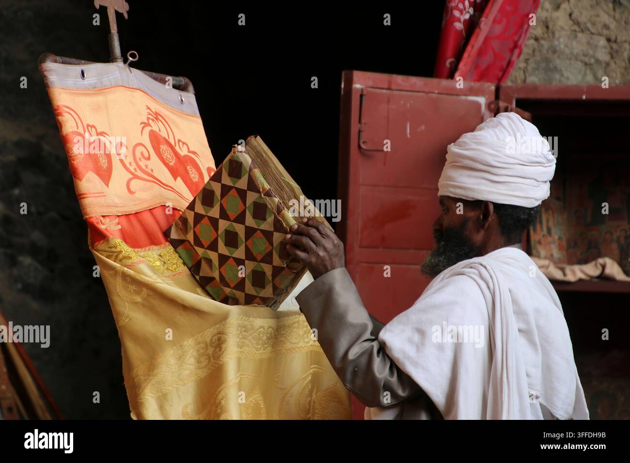 Prêtre orthodoxe éthiopien en tenue traditionnelle tenant un livre religieux sacré, participant à des rituels anciens et préservant le patrimoine spirituel en Banque D'Images