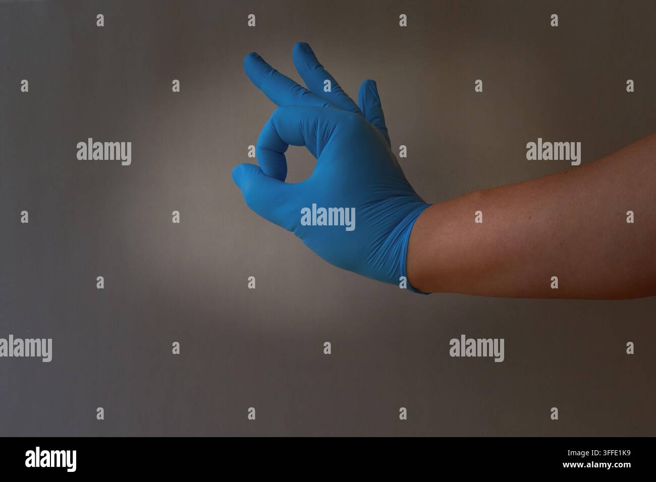 Une main d'une personne portant un gant médical bleu montre le chiffre 0 ou le signe OK Banque D'Images