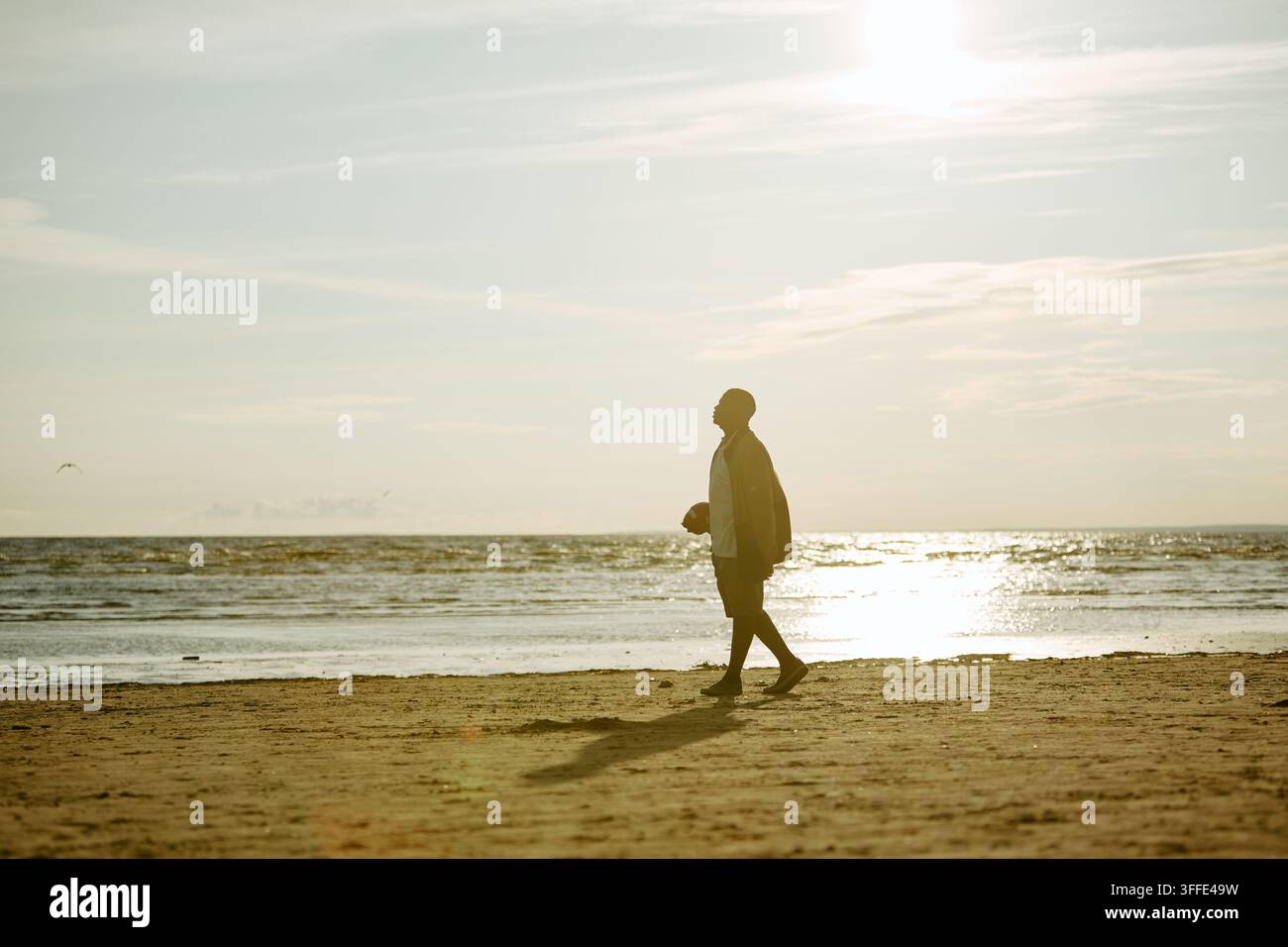 Homme noir marchant le long du rivage ensoleillé pendant des vacances Banque D'Images