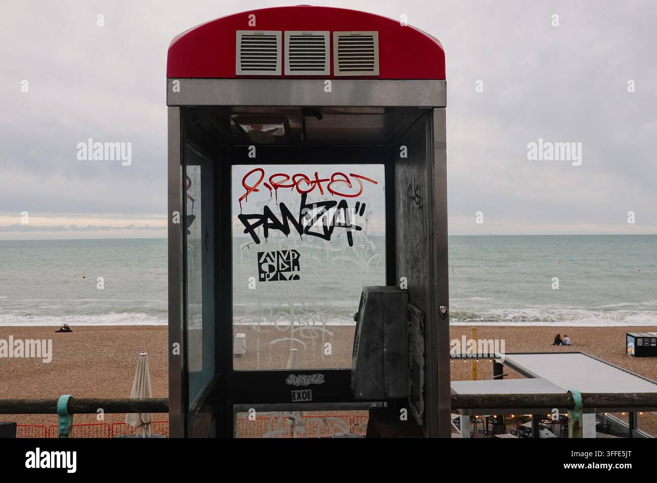 Une cabine téléphonique abandonnée couverte de tags de graffitis sur la promenade du front de mer avec la mer à Brighton, en Angleterre. Banque D'Images