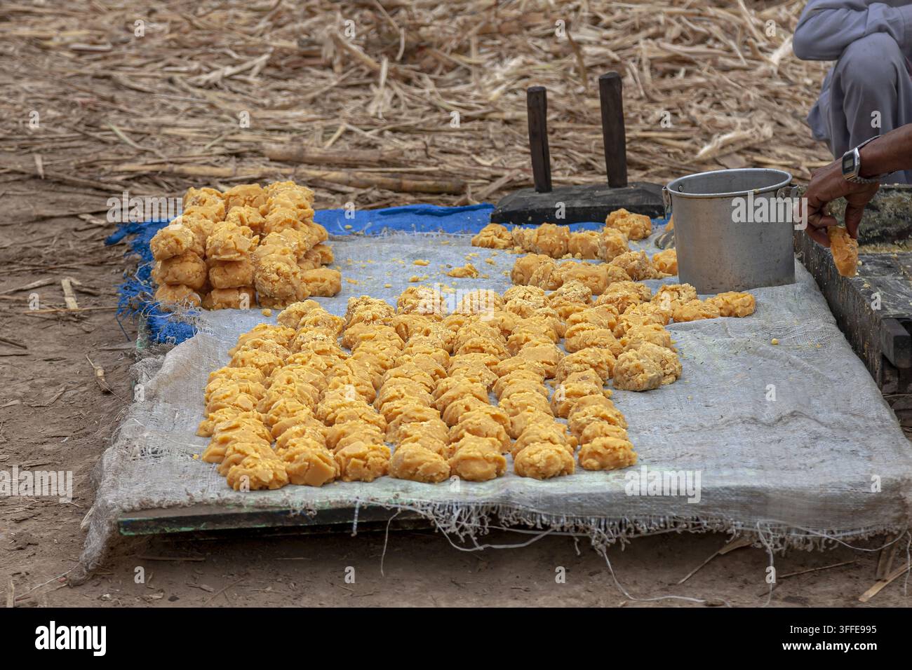 Vue de monticules de jaggery fraîchement préparés exposés sur un tissu lors de la production traditionnelle de sucre de canne à Multan, au Pendjab, au Pakistan. Banque D'Images