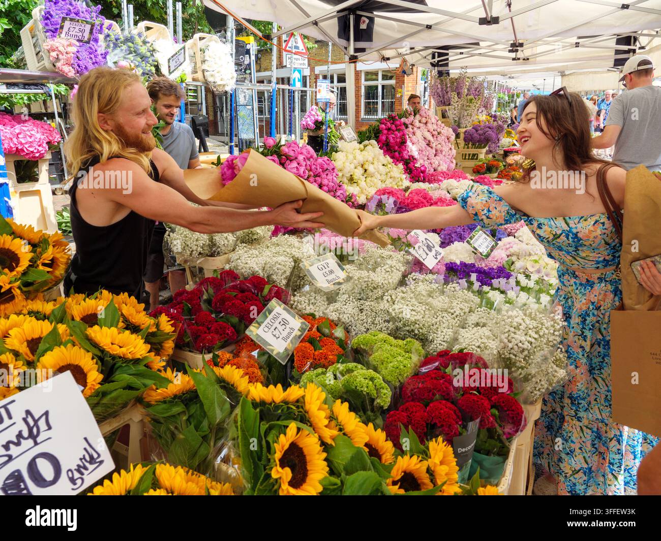 Jeune femme faisant ses courses à un étal du marché de Columbia Road Flower Market, Londres, Royaume-Uni Banque D'Images