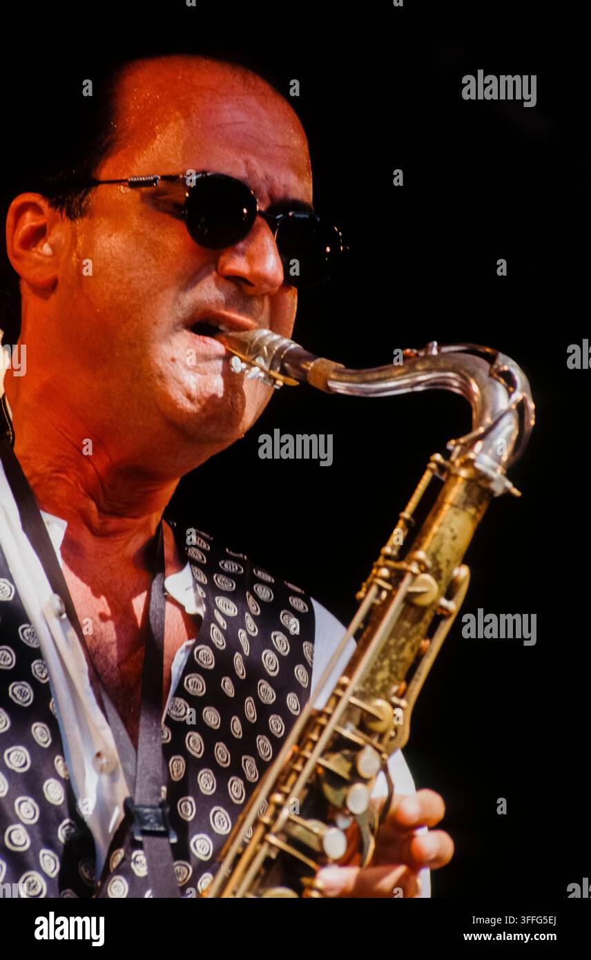 LONDON, UK - 27 JUIN 1993 : Maître de jazz fusion américain et saxophoniste Michael Brecker en performance live sur scène avec le groupe Brecker Brothers lors du festival Jazz on a Summer's Day organisé à l'Alexandra Palace à Londres, Royaume-Uni, le 27 juin 1993. Brecker est capturé en portrait rapproché au milieu d'un solo jouant son saxophone ténor, portant des lunettes de soleil sombres et un gilet noir et blanc distinctif par-dessus une chemise blanche à col. Cette photographie couleur archivée de 35 mm enregistre la tournée historique de réunion du duo iconique multi-Grammy des années quatre-vingt-dix. Banque D'Images
