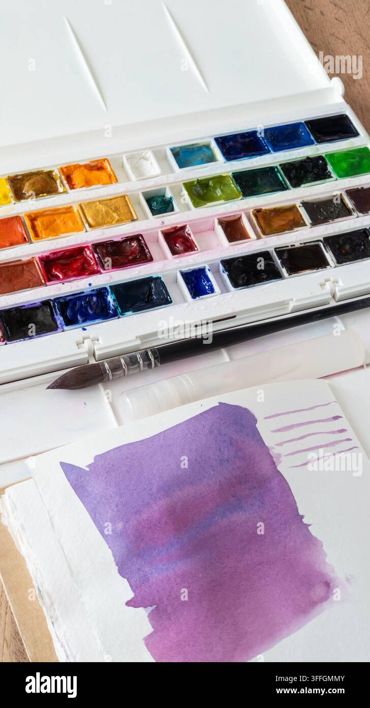 Fournitures artistiques pour la peinture à l'aquarelle. Peintures, gobelet d'eau, un pinceau, un mouchoir taché et une palette d'aquarelle sur une table blanche. Espace pour texte. Vertica Banque D'Images