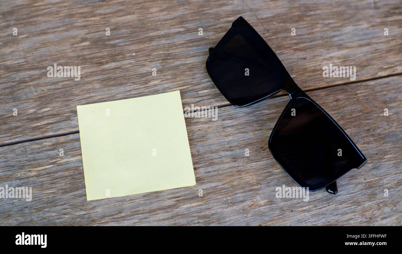 Note autocollante vierge et lunettes de soleil sur surface en bois Banque D'Images