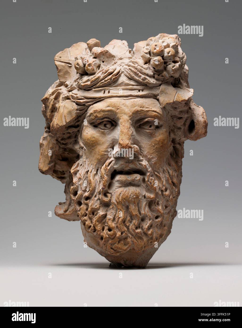 Tête en terre cuite de Dionysos grec ou romain, Ier siècle av. J.-C. Dionysos, dieu du vin et des plaisirs qu'il peut apporter, était extrêmement populaire durant les périodes hellénistique et romaine. Les rois grecs qui régnaient sur les terres conquises par Alexandre le Grand le prenaient comme divinité tutélaire, et les Romains, impressionnés par le luxe et la richesse de ces royaumes, remplissaient leurs villas privées d'images du dieu. Dionysos pouvait être représenté soit comme un homme barbu âgé, le compagnon de beuverie parfait, soit comme un beau jeune homme. Banque D'Images