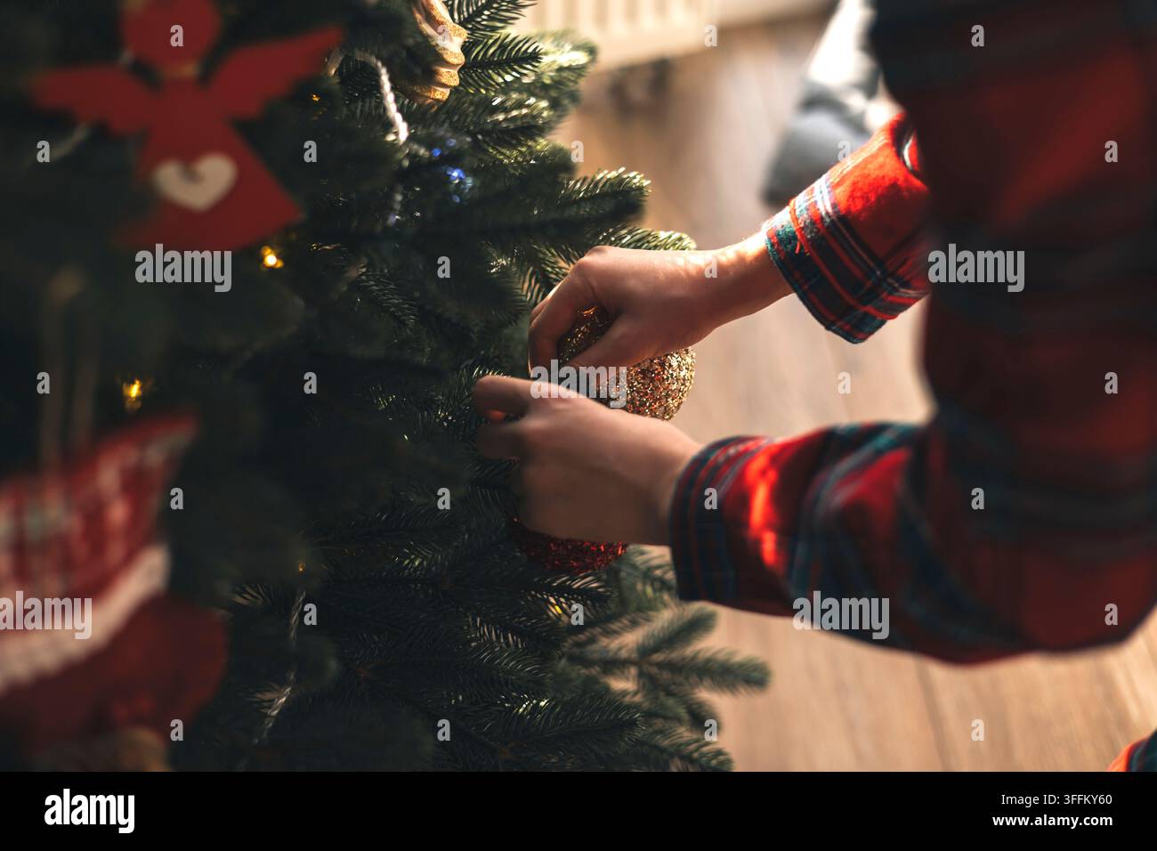 Enfant décorant un sapin de Noël avec une boule à la maison Banque D'Images