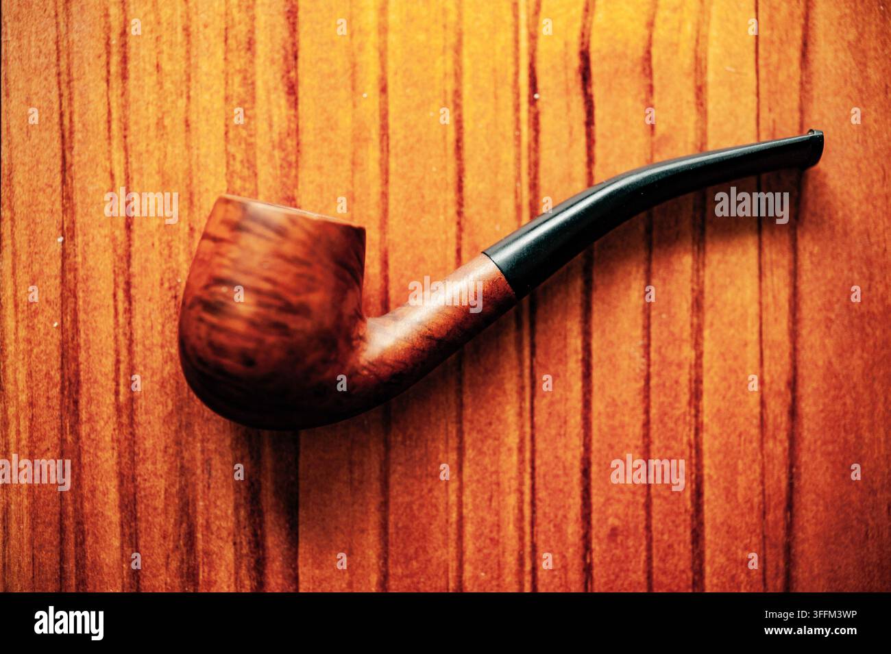 Pipe en bois classique avec un tuyau noir courbé sur une surface en bois chaud, photographiée comme une nature morte simple de style vintage Banque D'Images