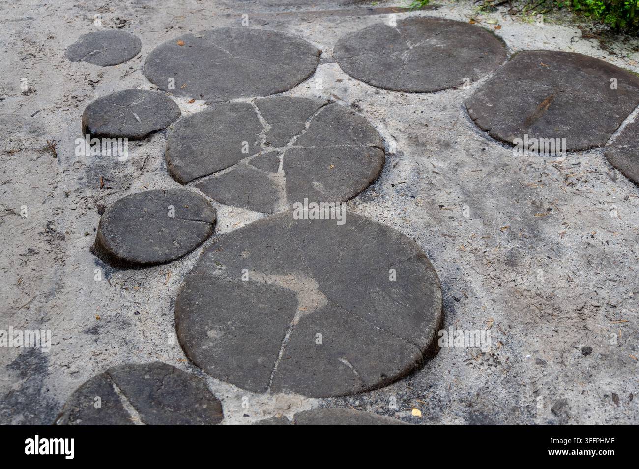 Des tranches de bois circulaires formant un chemin de pierres ponçantes sur le sable à Adrspach, République tchèque, conception de jardin créative, allée rustique Banque D'Images