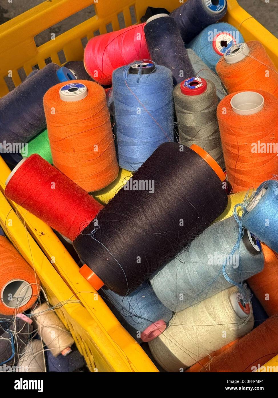 Bobines de fil colorées empilées dans des paniers en plastique sur un étal de marché à Sousse, Tunisie, un détail éclatant de fournitures de couture Banque D'Images