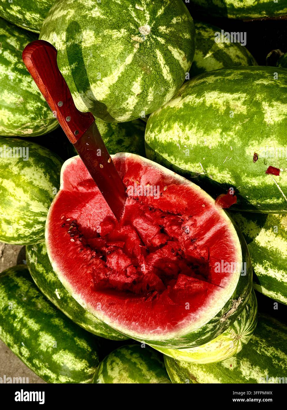 Pastèque coupée avec un couteau exposée parmi des pastèques entières sur un étal de produits frais à Tunis, Tunisie. Banque D'Images