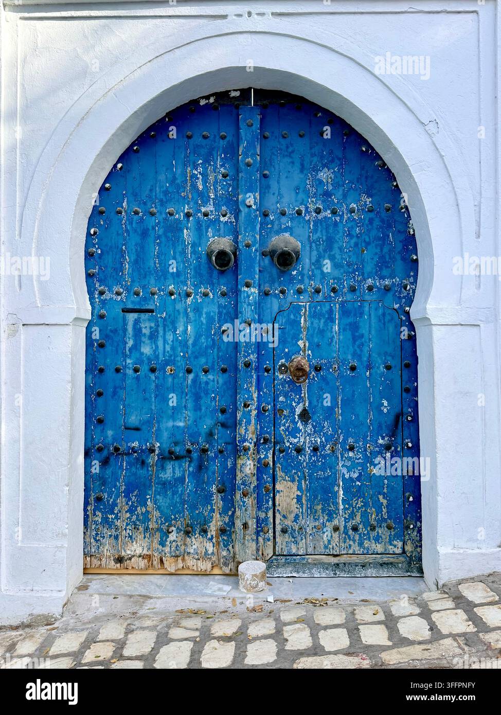 Porte bleue cloutée ornée sur une maison traditionnelles blanchies à la chaux à Sidi Bou Said, Tunis, Tunisie Banque D'Images
