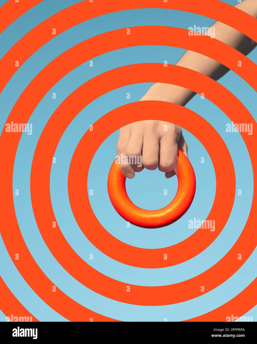 Composition médiatique surréaliste d'une main saisissant un anneau orange au-dessus de cercles concentriques audacieux, créant un design géométrique abstrait ressemblant à une cible sur un Banque D'Images