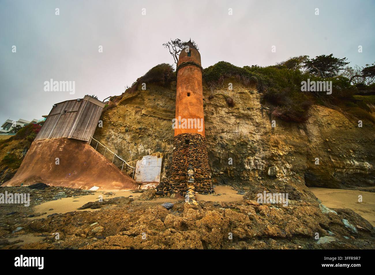 La célèbre tour Pirate s'élève fièrement contre des falaises dramatiques et la plage de sable de Laguna Beach en Californie. Ciel couvert et architecture historique m Banque D'Images