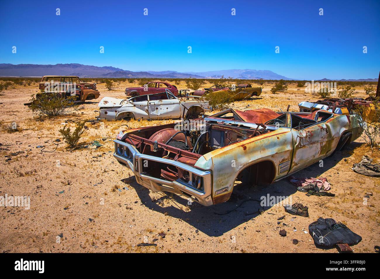 Voitures classiques abandonnées rouillant dans le désert de Mojave en Californie sous un ciel bleu éclatant Banque D'Images