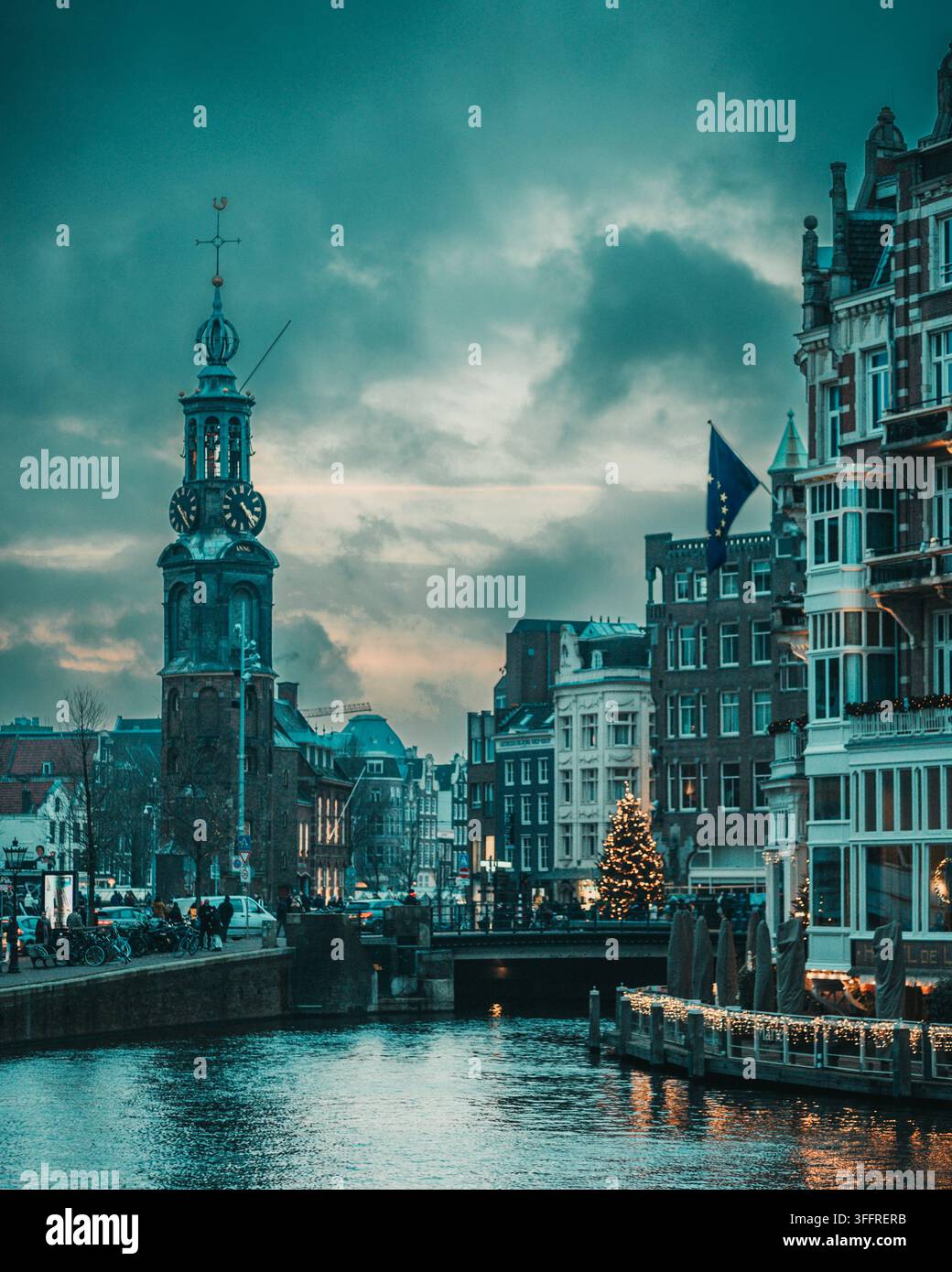 Munttoren et maisons historiques du canal dans le centre d'Amsterdam, Pays-Bas, reflétées dans l'eau au crépuscule pendant la saison de Noël Banque D'Images
